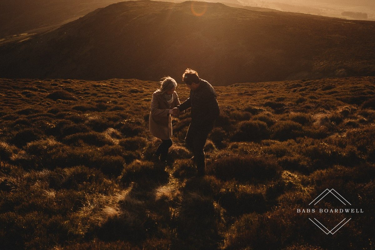 couple at sunset walking across the heather in North Wales