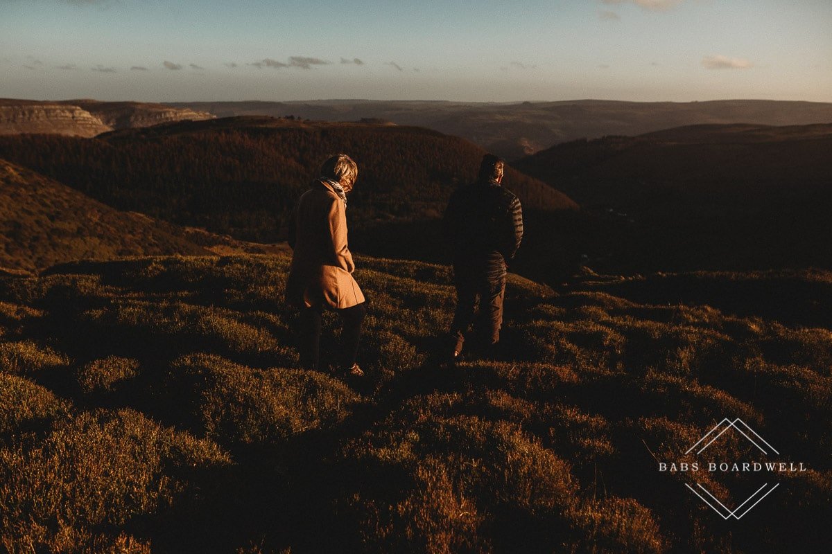 couple walking across the heather overlooking World's End in Llangollen at sunset