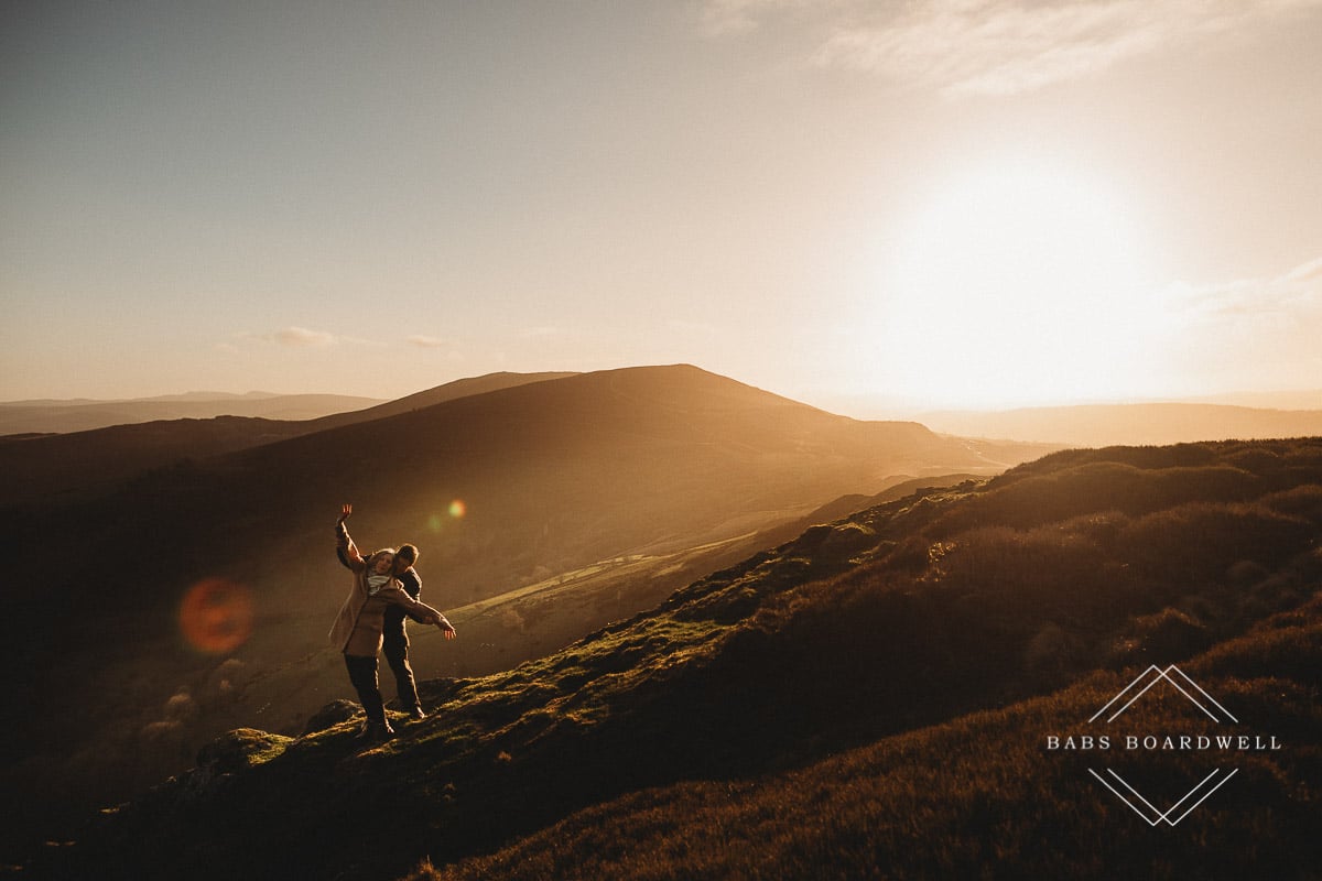couple pretending to be on the Titanic in the hills in North Wales at sunset