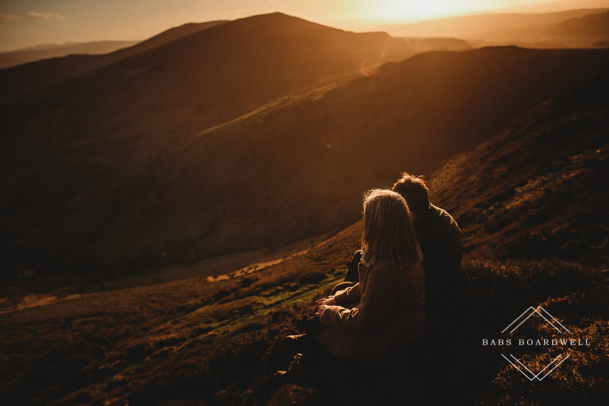 couple sitting next to each other overlooking Welsh scenery at sunset