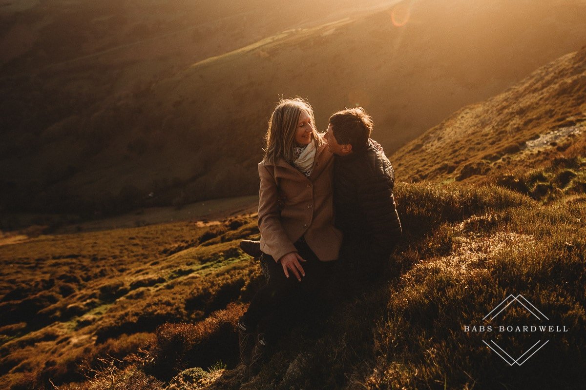 couple sitting next to each other overlooking Welsh scenery at sunset