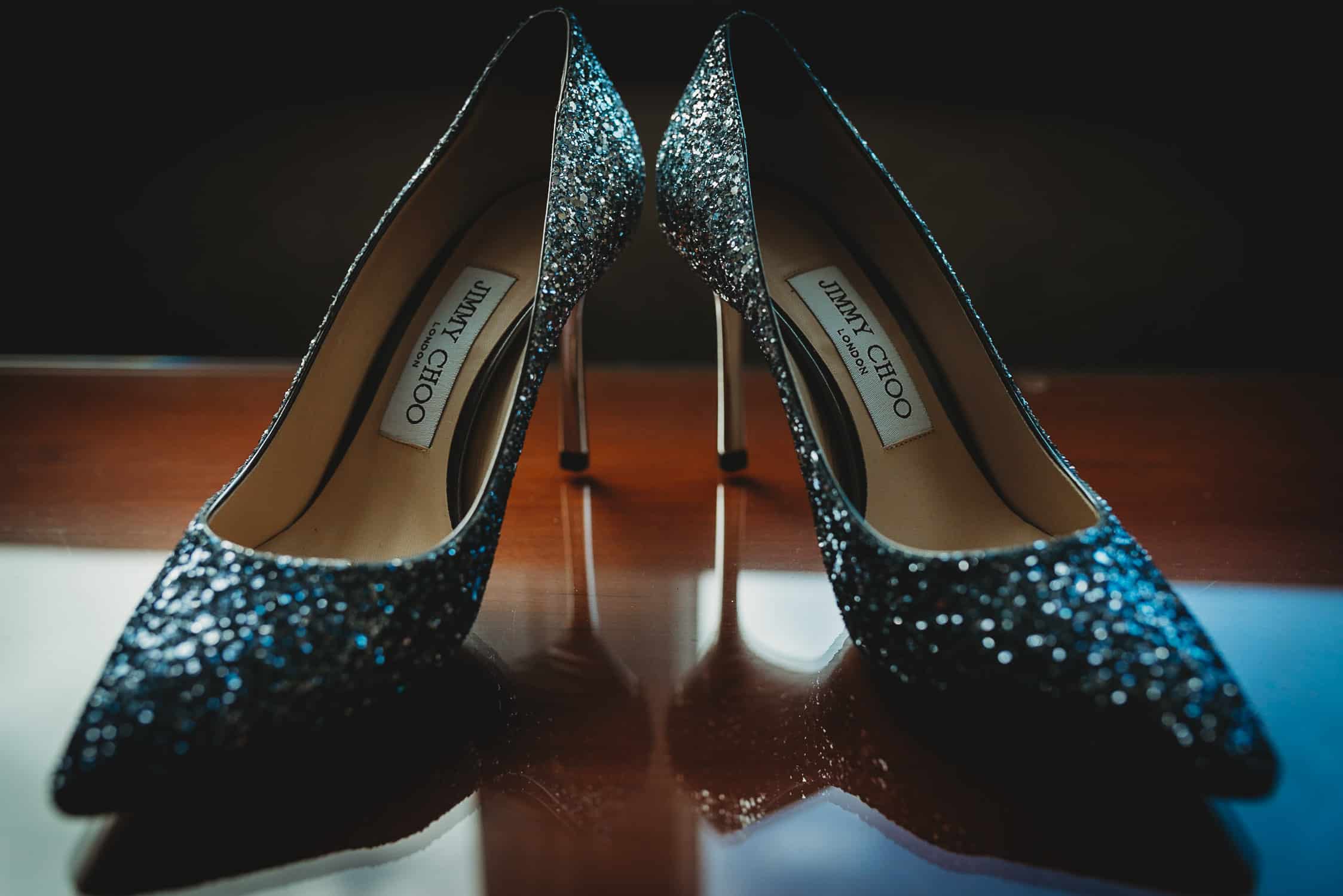 close-up of shiny Jimmy Choo shoes on a glass table