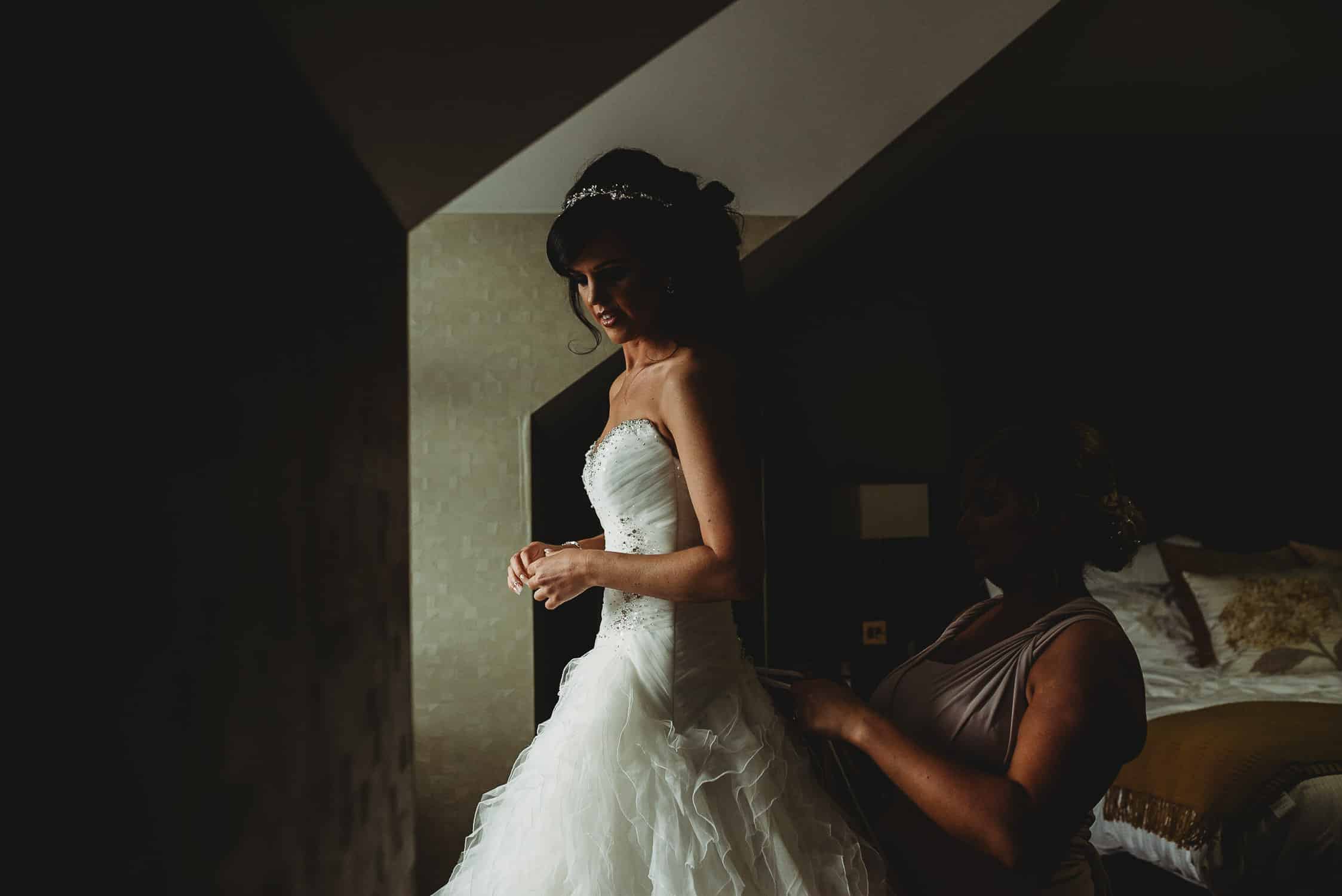 bride's dress being fastened by one of her bridesmaids