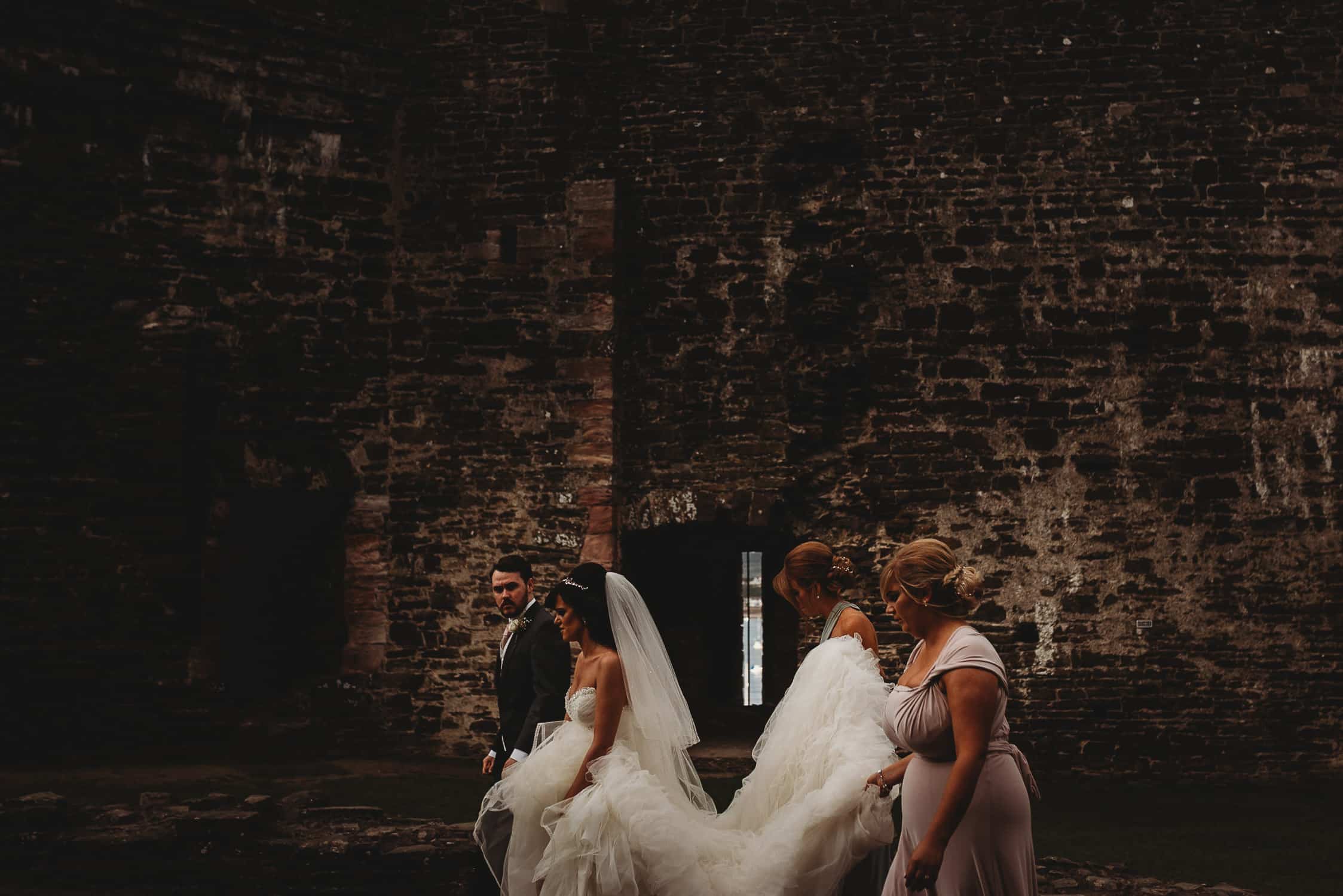 bride & groom walking with bridesmaids at Conwy Castle
