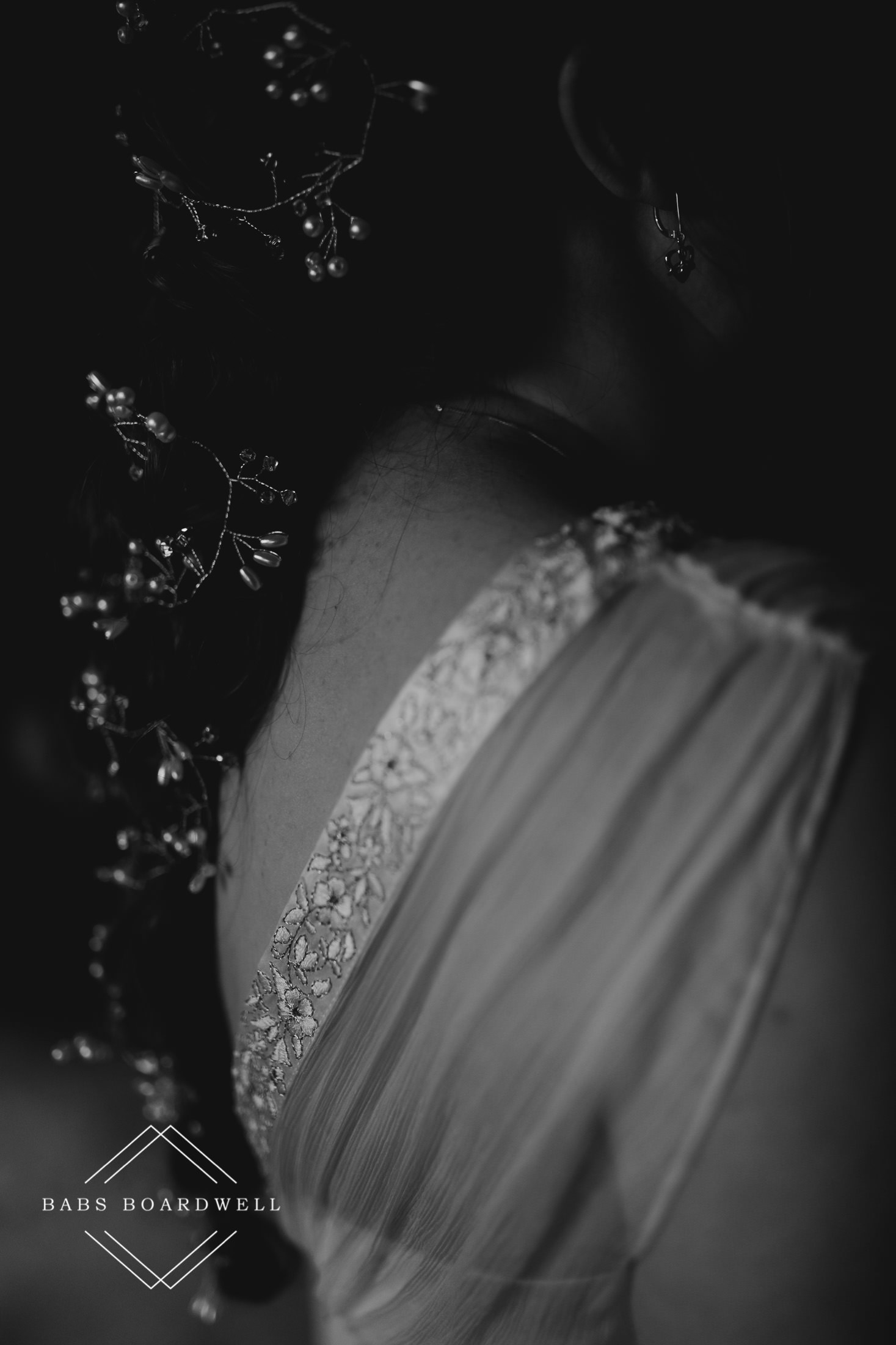 black and white close-up of bride's braided hair and one of her shoulders with lace wedding dress detail