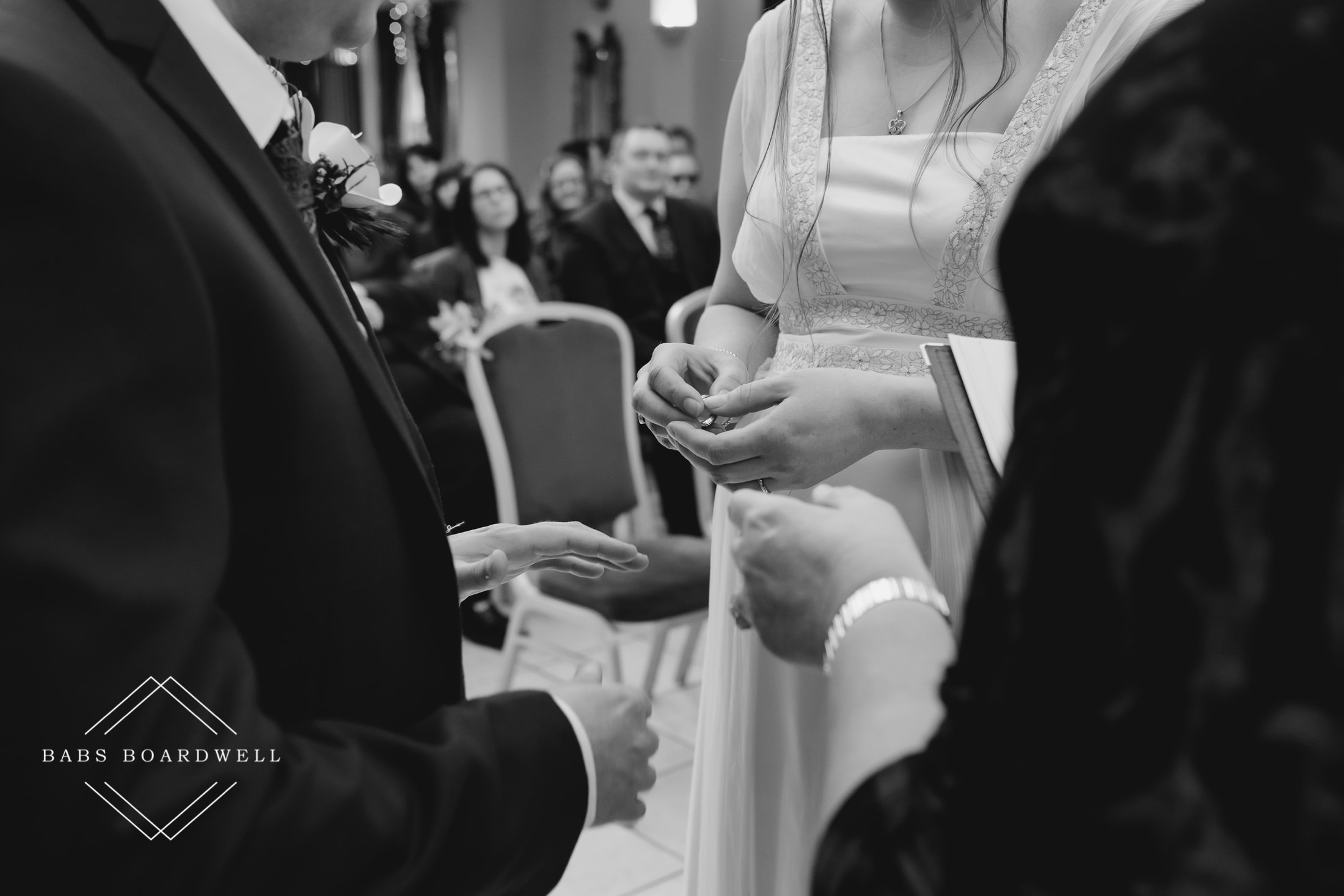 black and white image of the bride and groom exchanging rings
