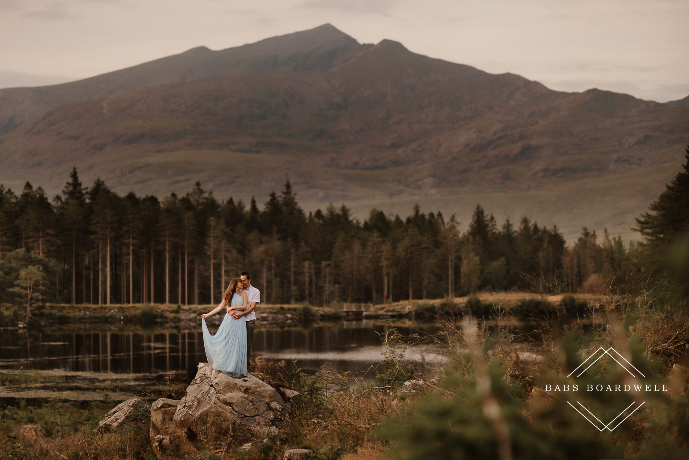 groom and bride wearing a blue wedding dress on a tree stump with Snowdon in the background by North Wales Wedding & Elopement Photographer