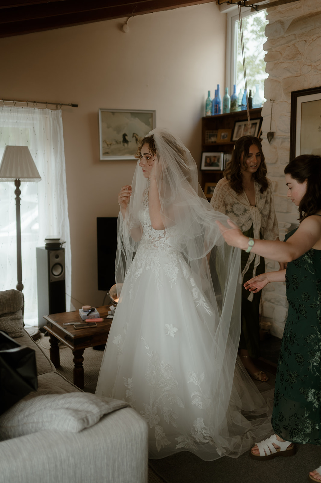 bride getting ready and having her veil put into place by her bridesmaids at home