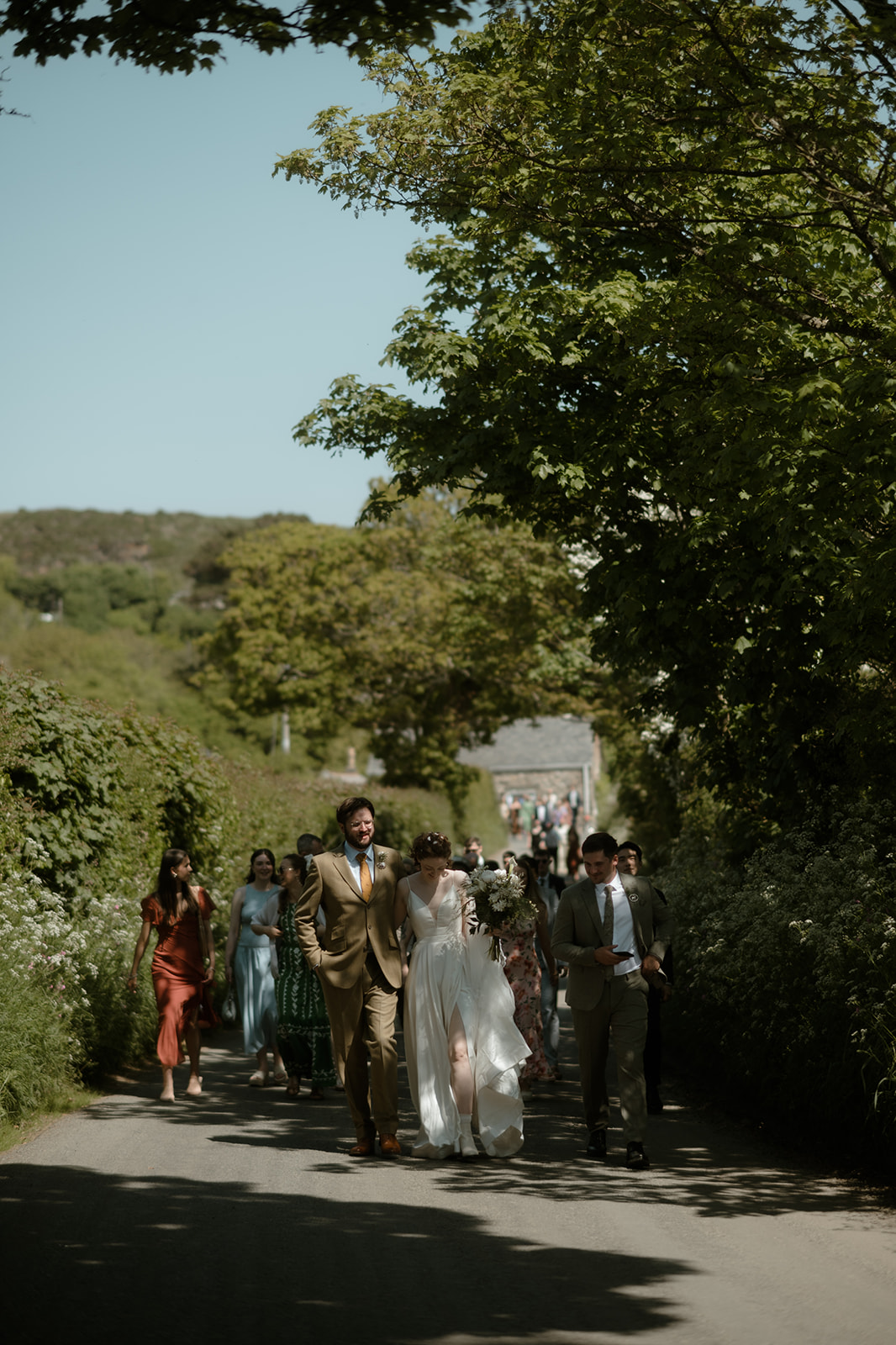 bride and groom walking back to NightSky glamping after their church wedding ceremony leading their guests