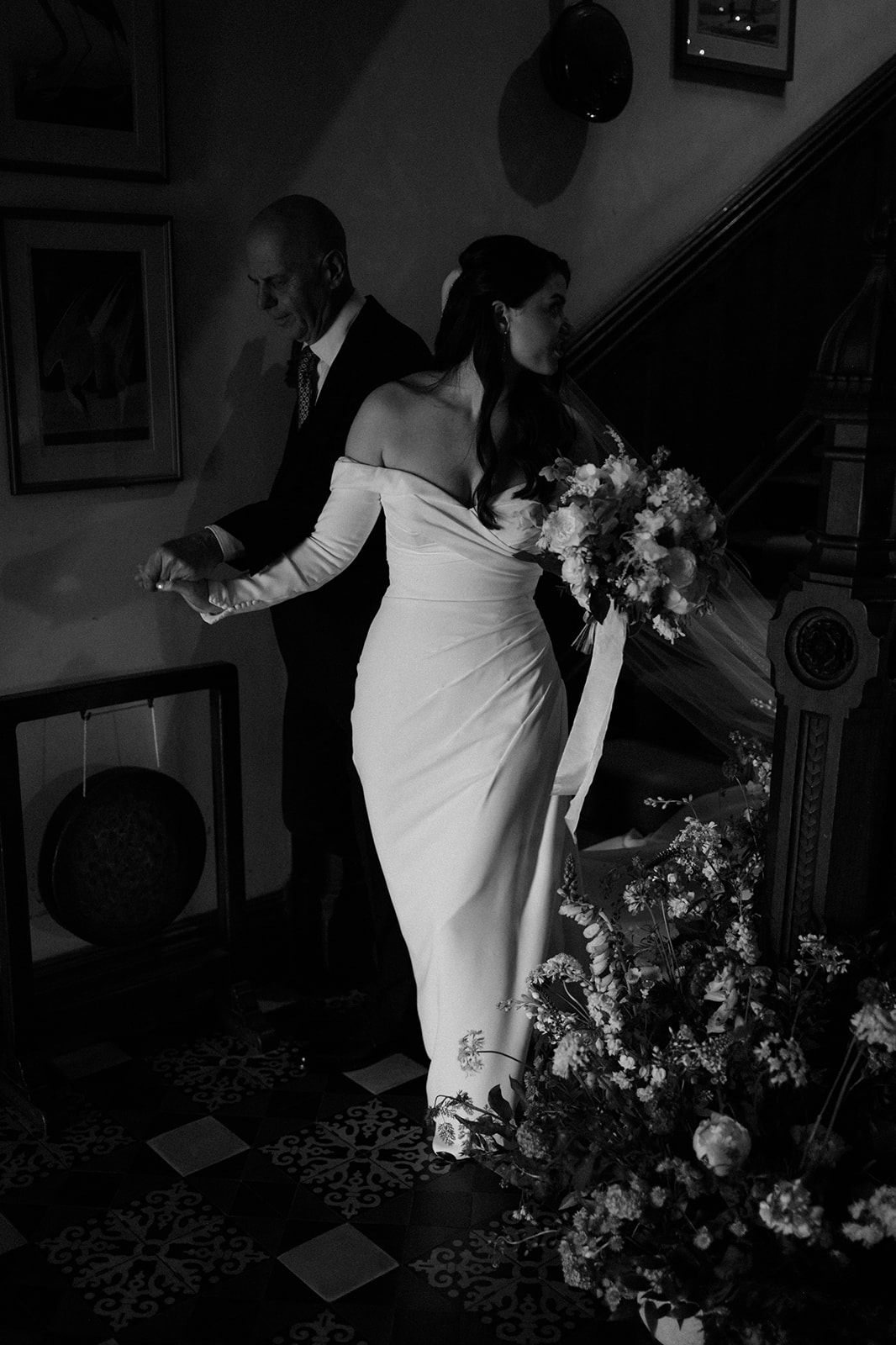 black and white image of bride being walked down the stairs by her father