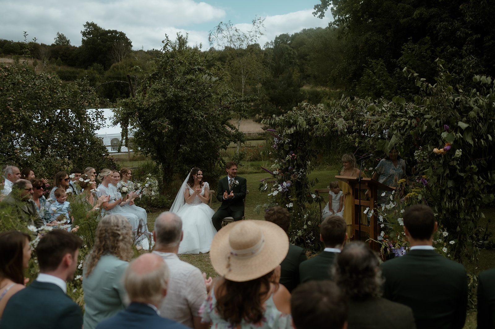 couple during their wedding ceremony on a farm surrounded by greenery and their friends and family in Mid Wales