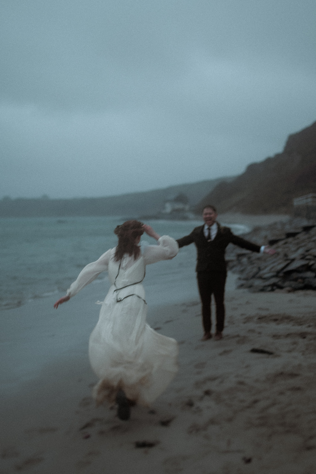 bride running towards her groom on Nefyn beach during a storm