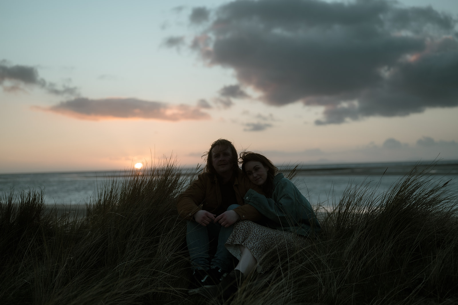 couple at sunset on a beach with their dog