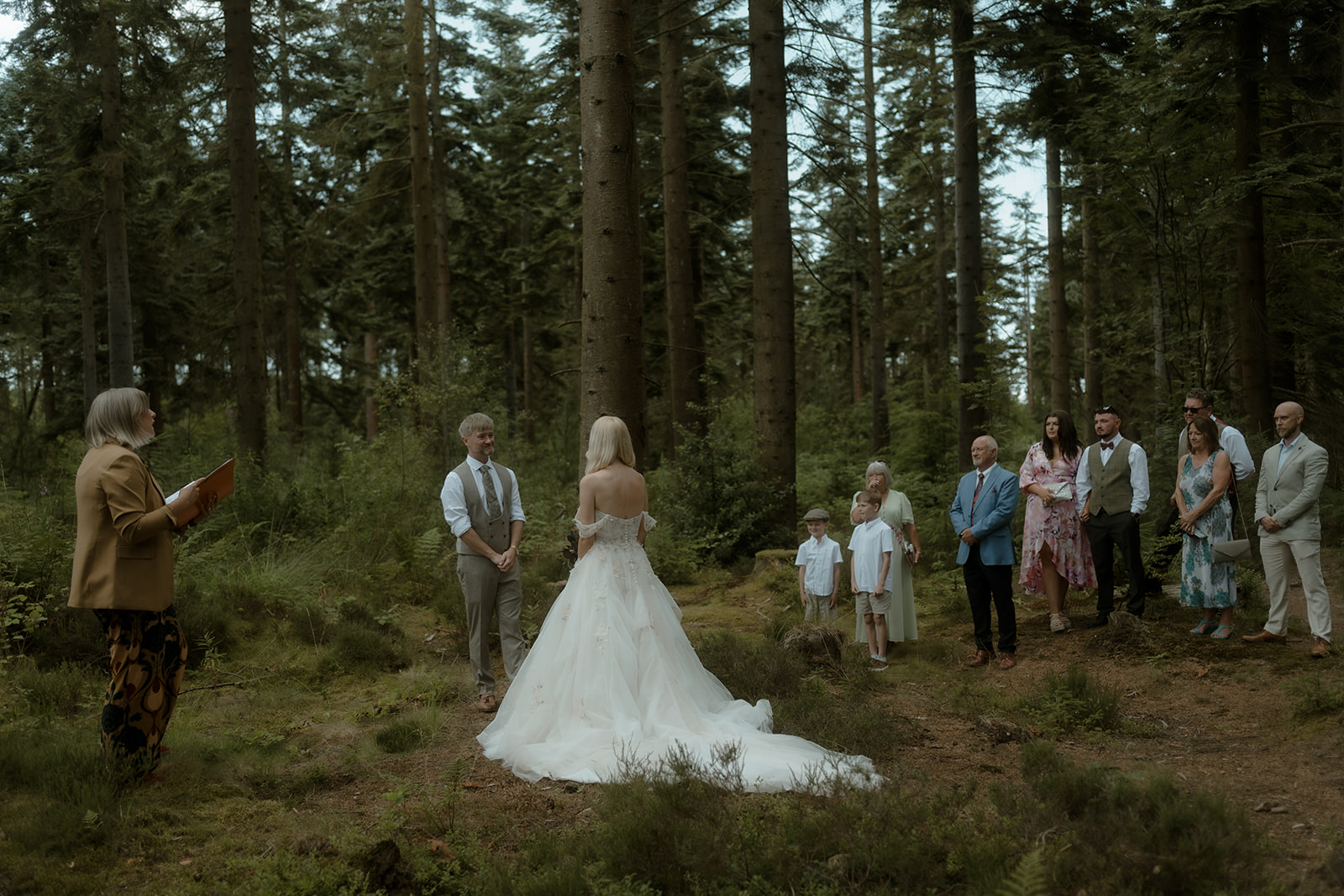 a couple and their celebrant exchanging vows in front of a small number of family members in a forest in North Wales